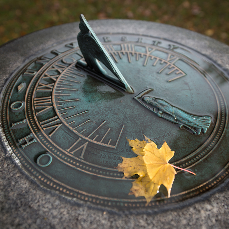 The Ohio University sundial with a yellow maple leaf