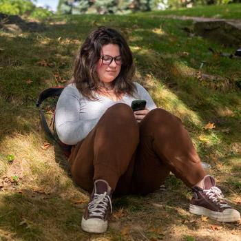 Student sitting outdoors on her mobile phone