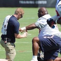 Chris Barrett kneeling with football player on field
