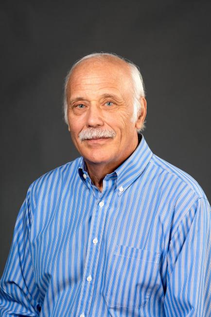 Headshot of Bill Elasky in a blue striped dress shirt.