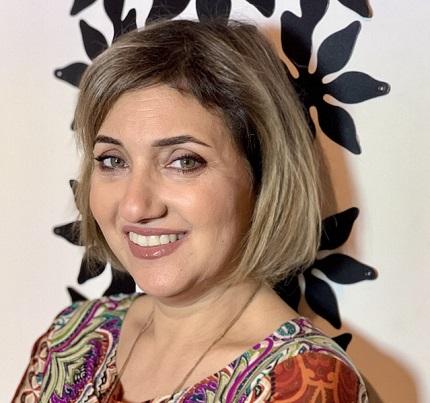 Headshot of a smiling Sara Salloum in a print top 