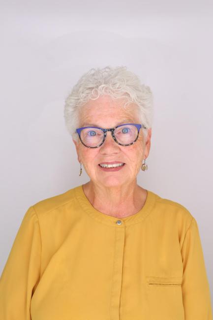Headshot of a smiling Cindy Hartman with glasses yellow blouse