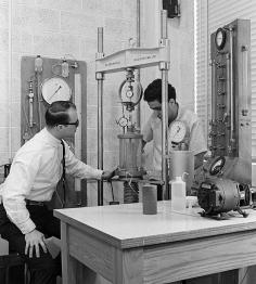 Nostalgic black and white image of past civil engineers working with lab equipment.
