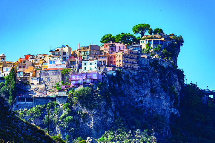 Colorful houses sitting on the side of a large cliff.