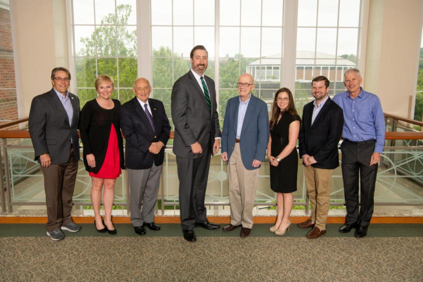 Eight members of the Cutler Scholars Advisory Board pose in front of a window
