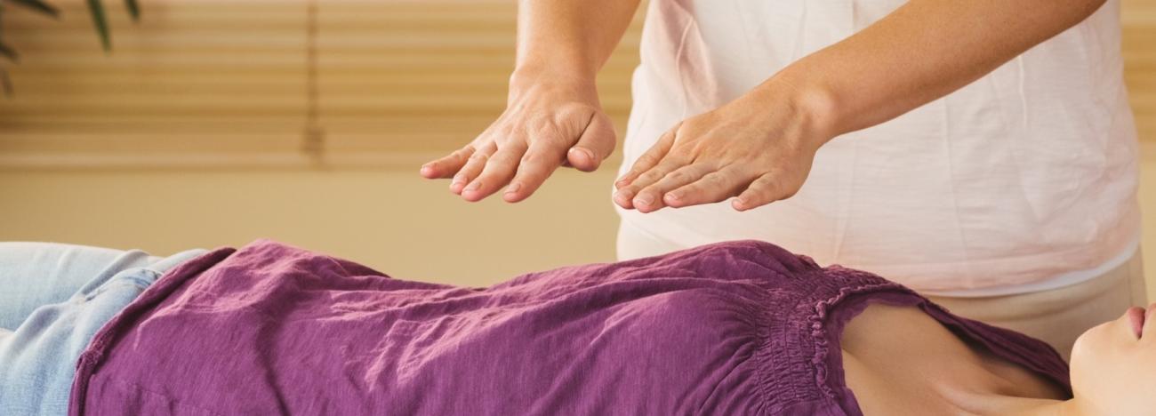 Reiki Master placing hands a few inches above a client's body