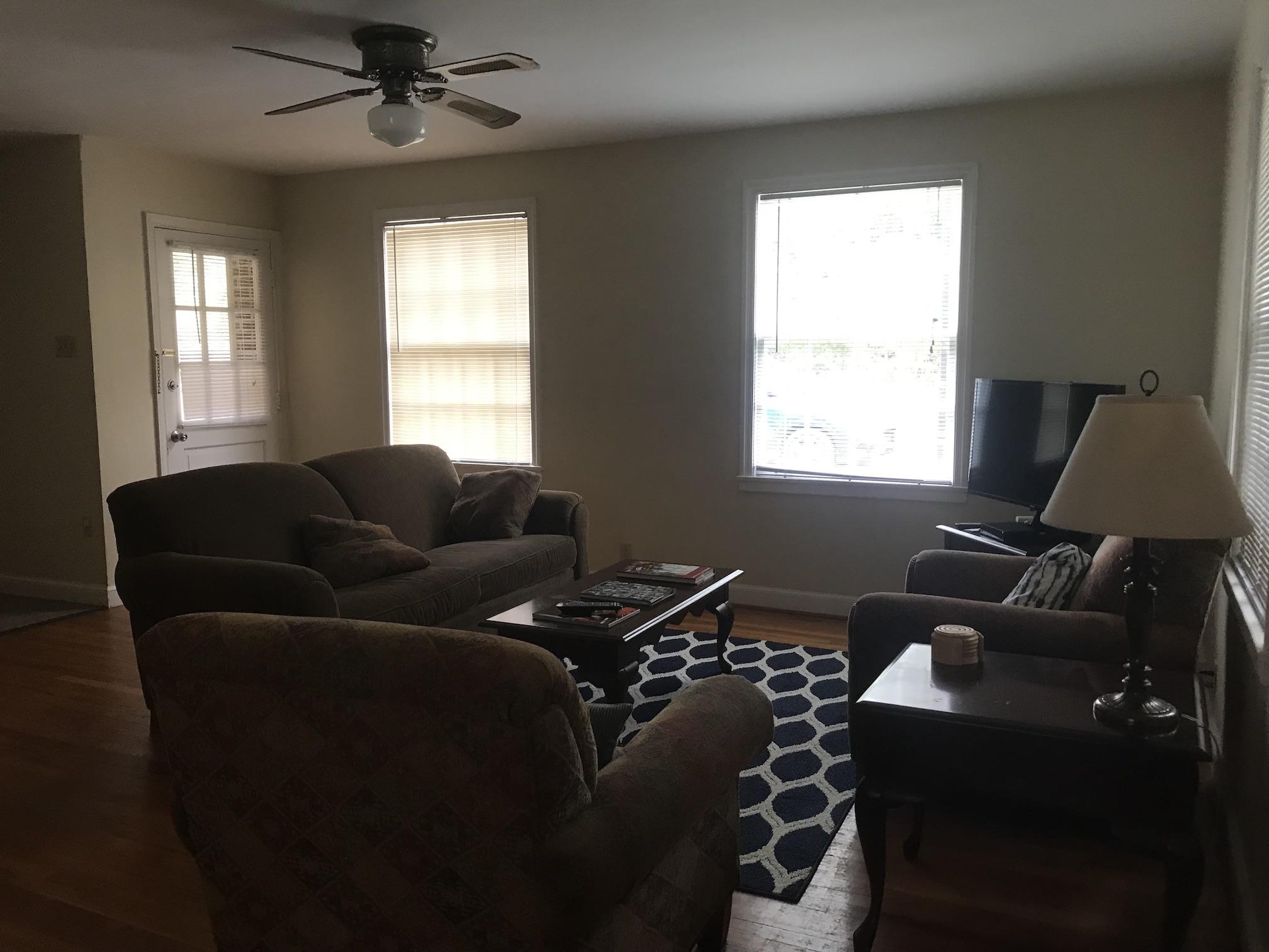 Living room with a wood floor, an exterior door, and windows