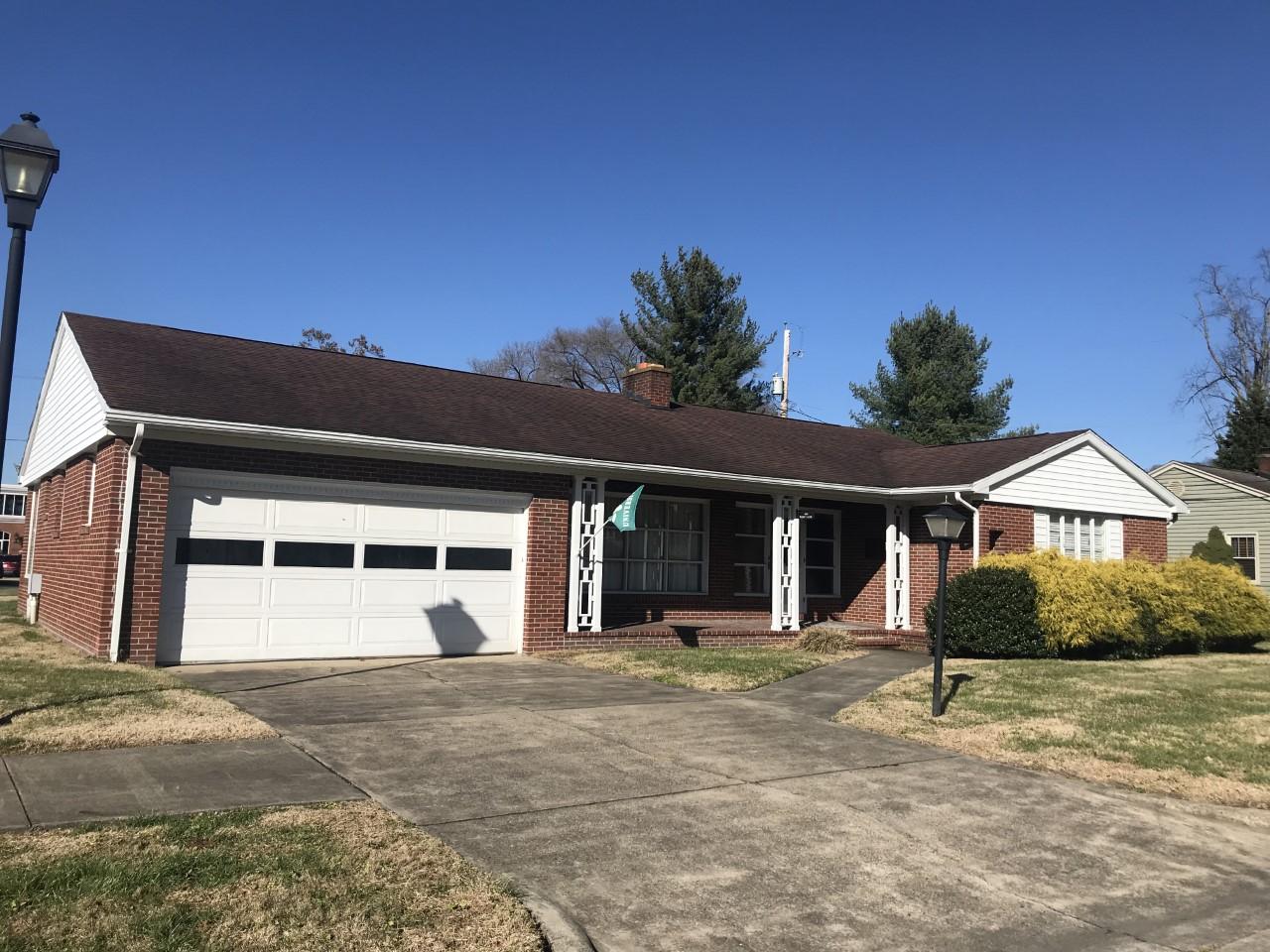 Front of brick ranch-style house with garage and driveway, and a front porch