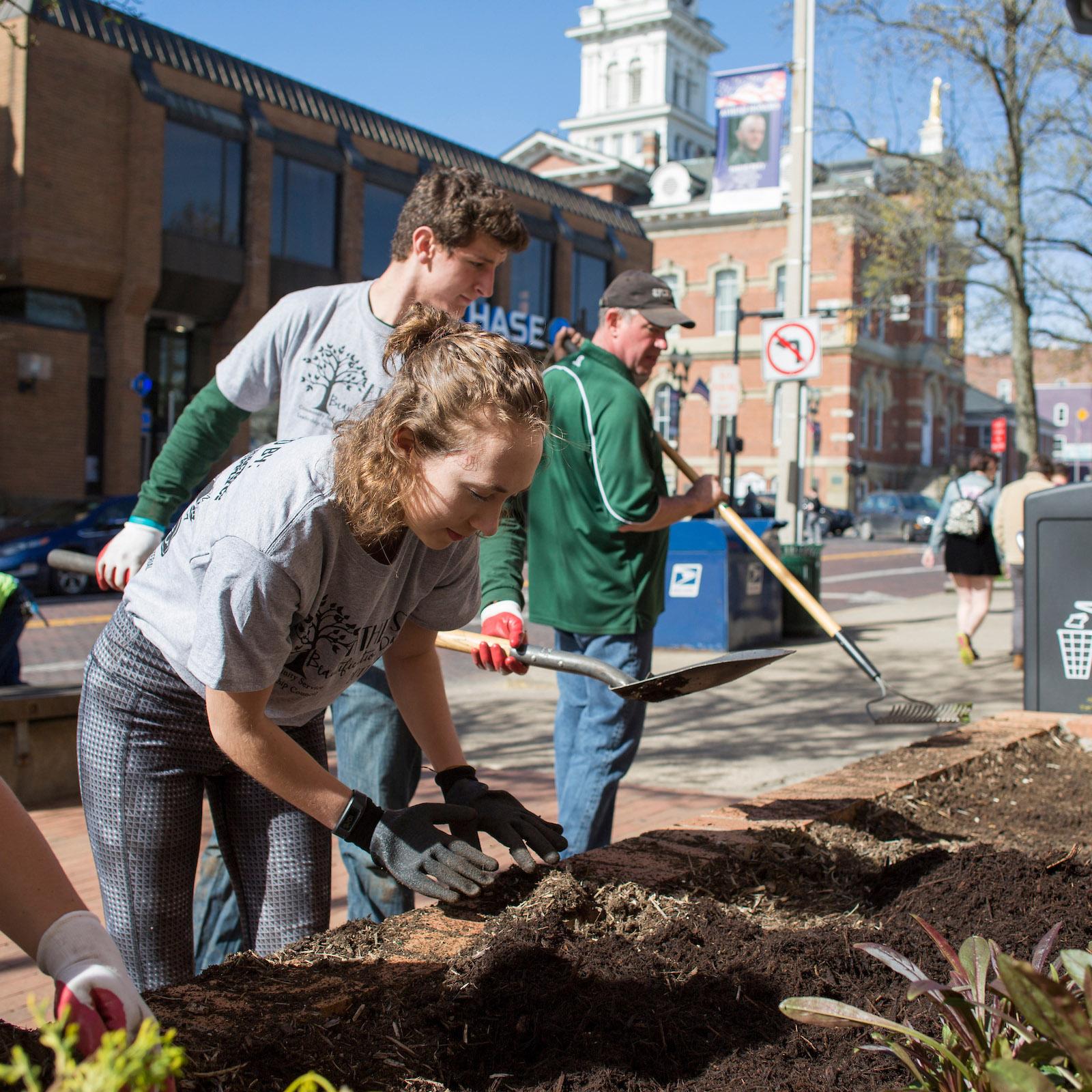 Volunteers help pull weeds and add new plants outside of the City Building
