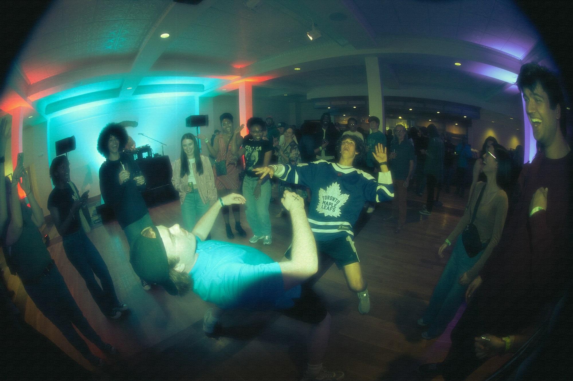 Students leaning back dancing on dance floor through fish eye camera lens