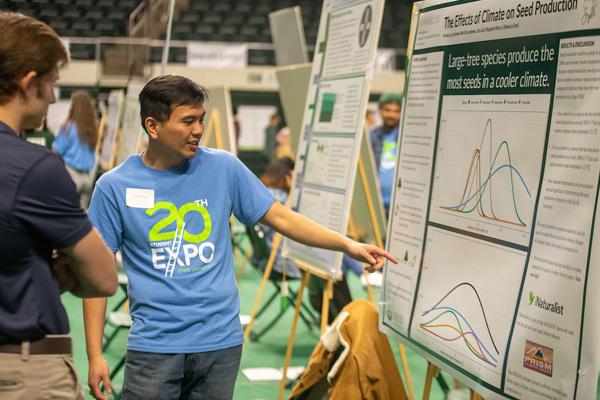 Student points to their poster during the student research expo