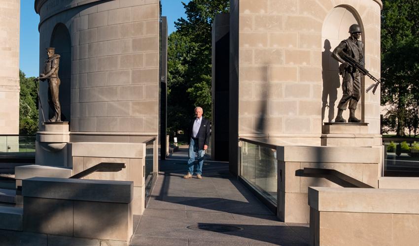 P. Joseph “Joe” Mullins, MFA ’78, is pictured with two of the four bronze statues he sculpted for the West Virginia Veterans Memorial.