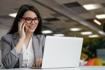 Digital communication professional multitasking on phone and laptop