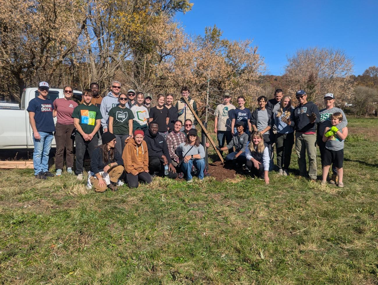 A group of people around a freshly planted tree.