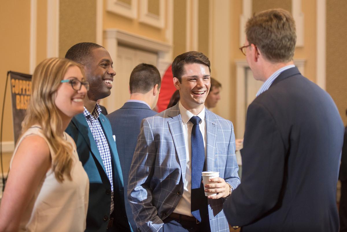 Students and faculty talk to one another at a conference.