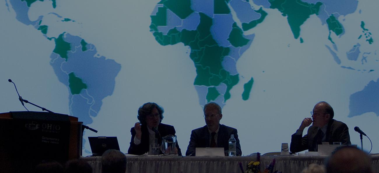 Panelists in front of a world map at a conference at Ohio University