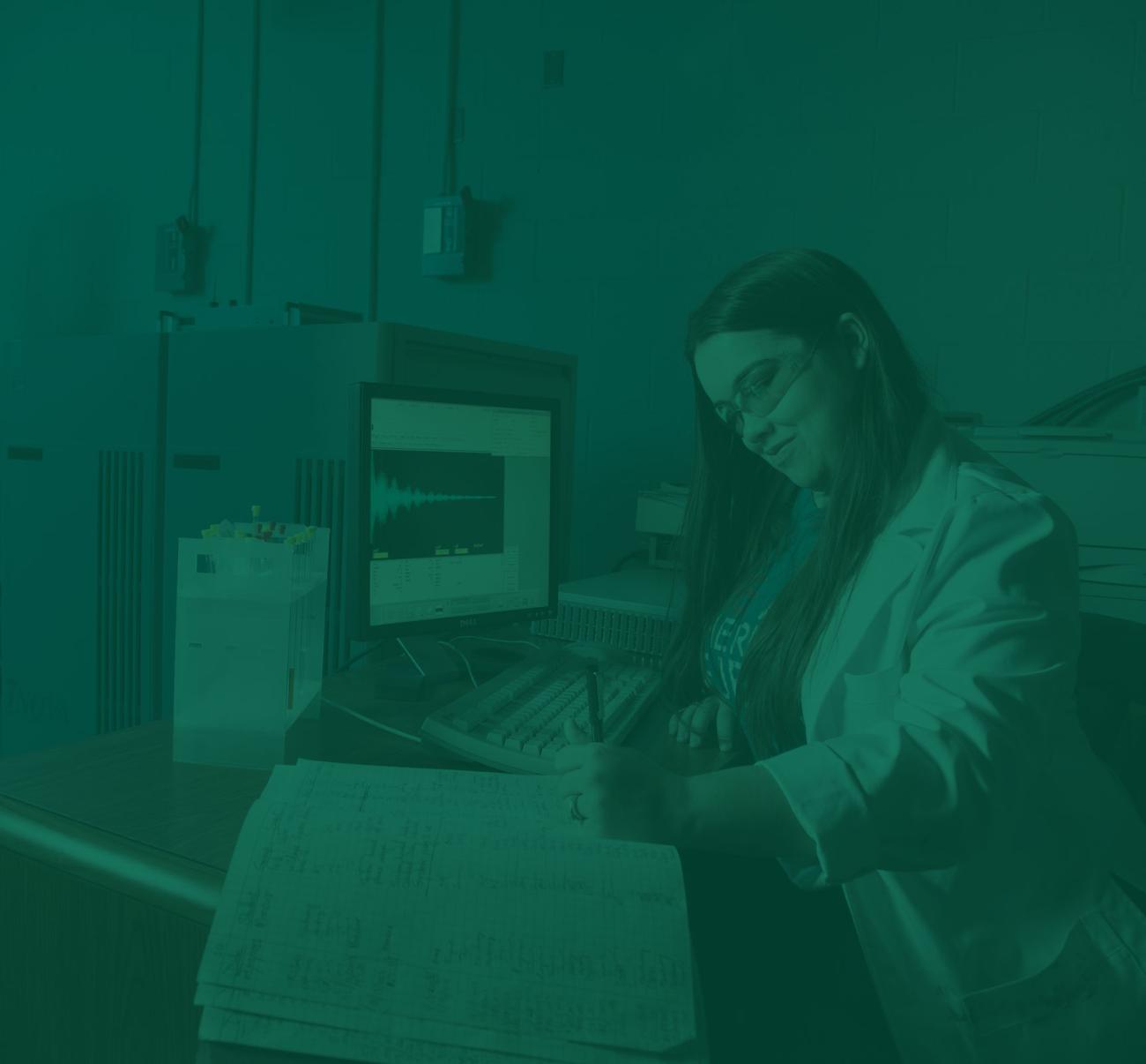 A chemistry student takes notes sitting at a computer