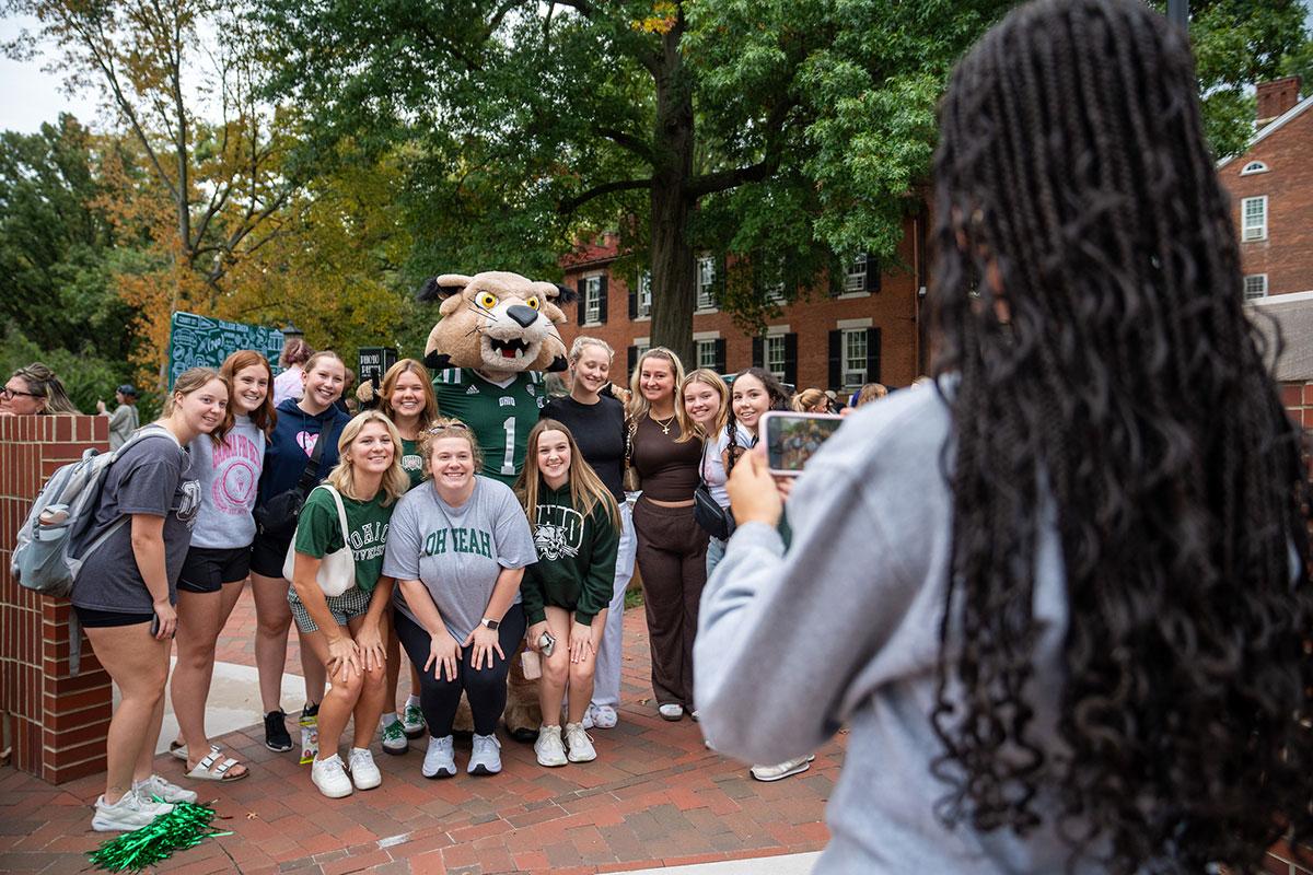 A group of Ohio University students gets their photo taken with Rufus Bobcat