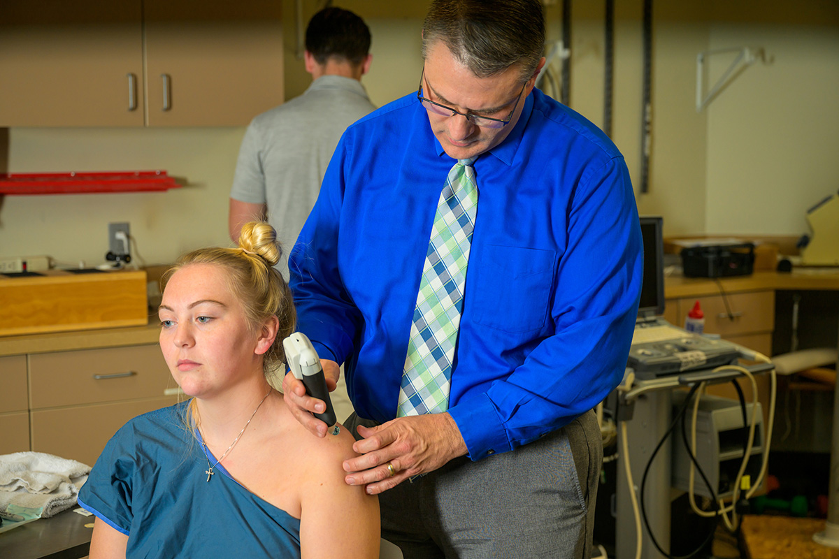 Dr. Neil Evans tests a patient's shoulder.