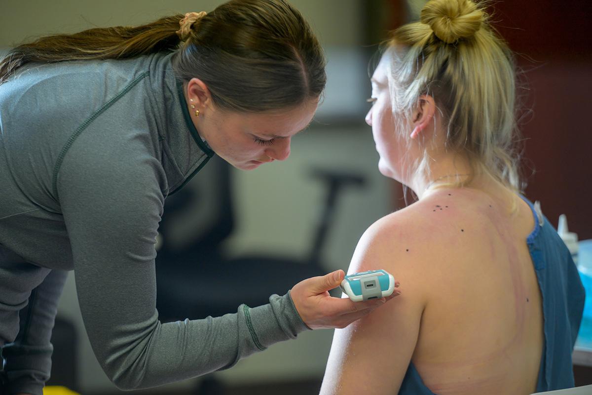 A student studies a patient's shoulder.
