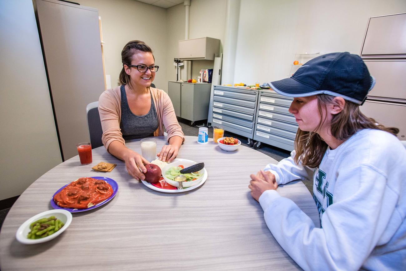 Student and teacher talking to each other at table looking at food