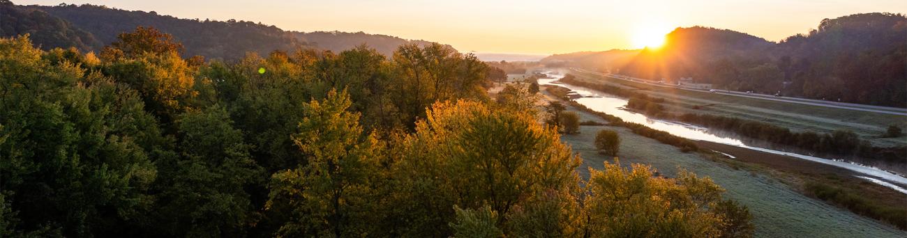 An aerial view of trees and a waterway during sunset.