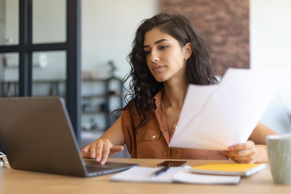 Woman at a desk with papers and a laptop