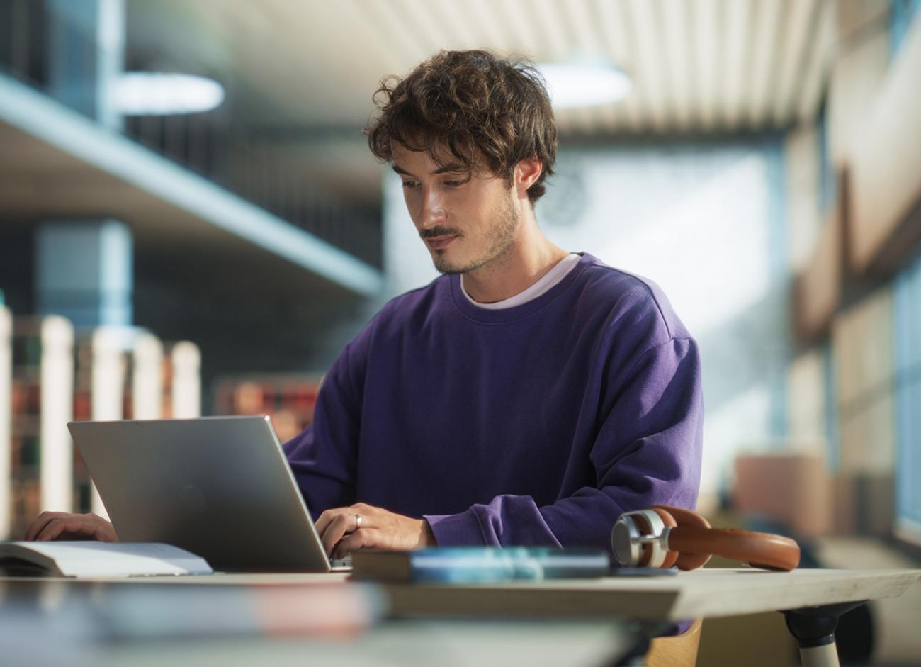 man sitting at a desk with a laptop and notebook next to him