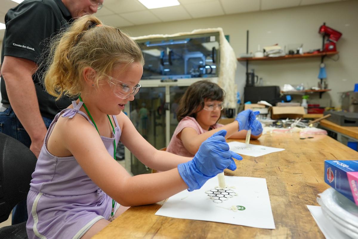 2 children doing experiments while wearing purple gloves