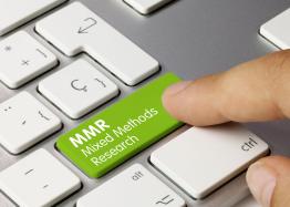 A computer keyboard with a finger pointing toward one green button labeled "MMR Mixed Methods Research"