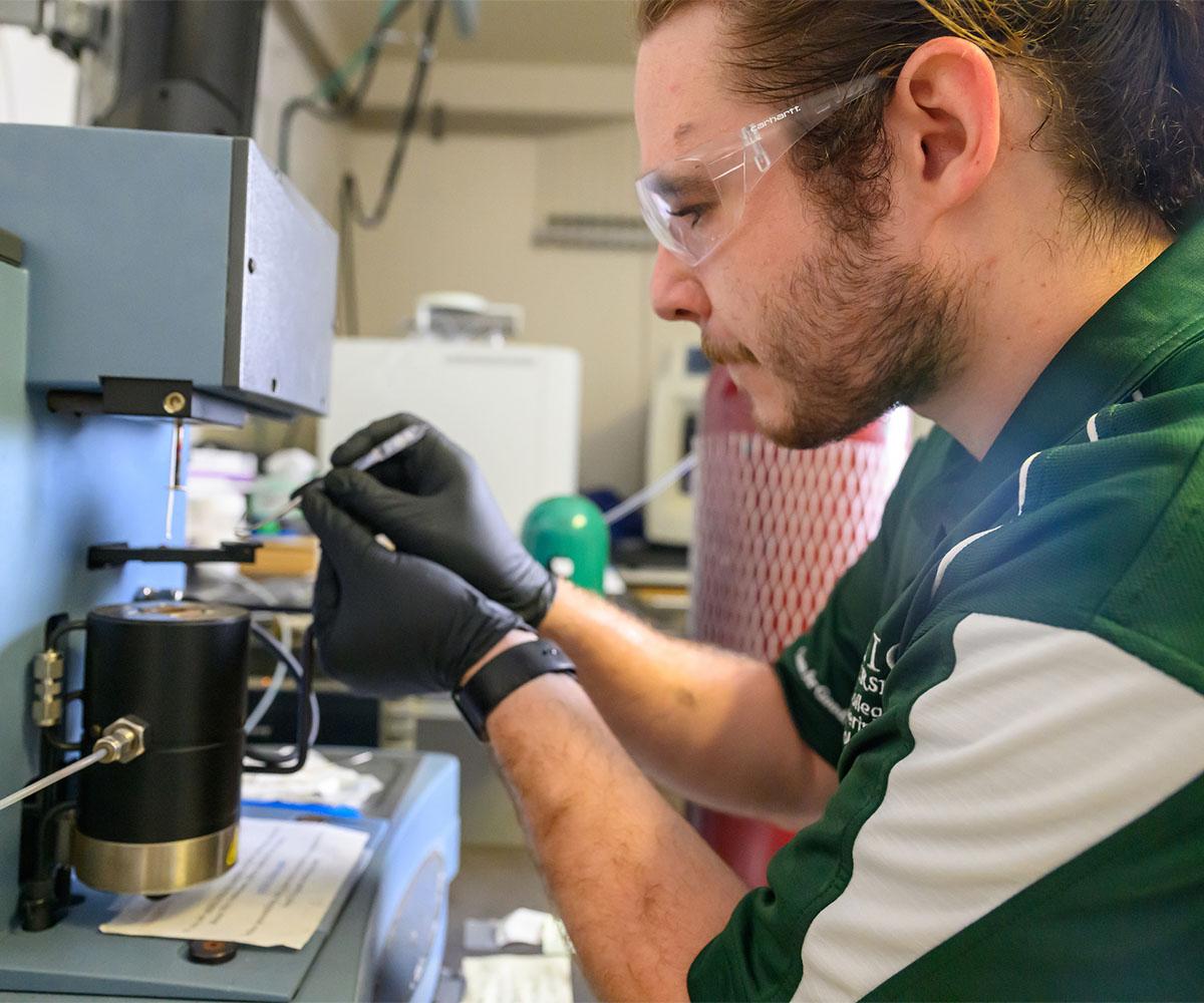 A student works on a machine in a lab.