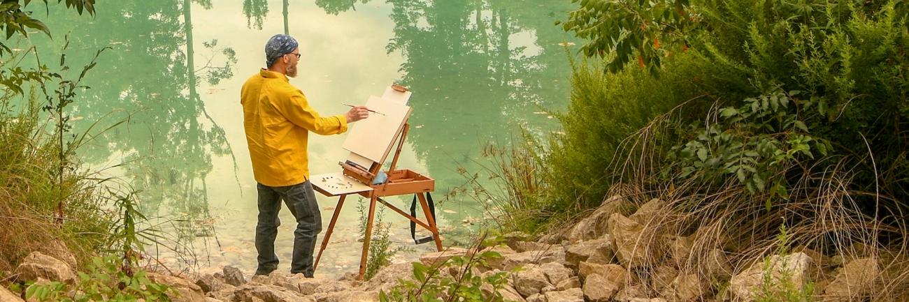 Professor John Sabraw painting beside water.