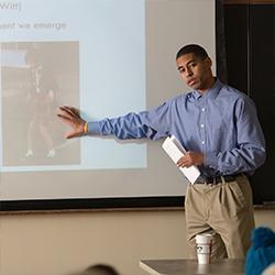 Person pointing at a projector screen in a classroom