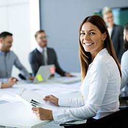 woman sitting at a conference table with other workers in suits