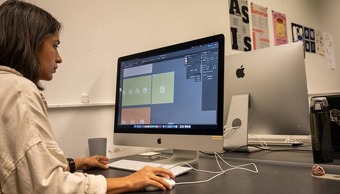 A student workin in Adobe on an Apple computer.