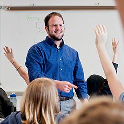 Teacher in a classroom answering students with raised hands