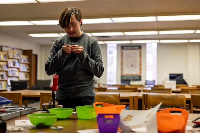 A student examines a table covered with button-making supplies