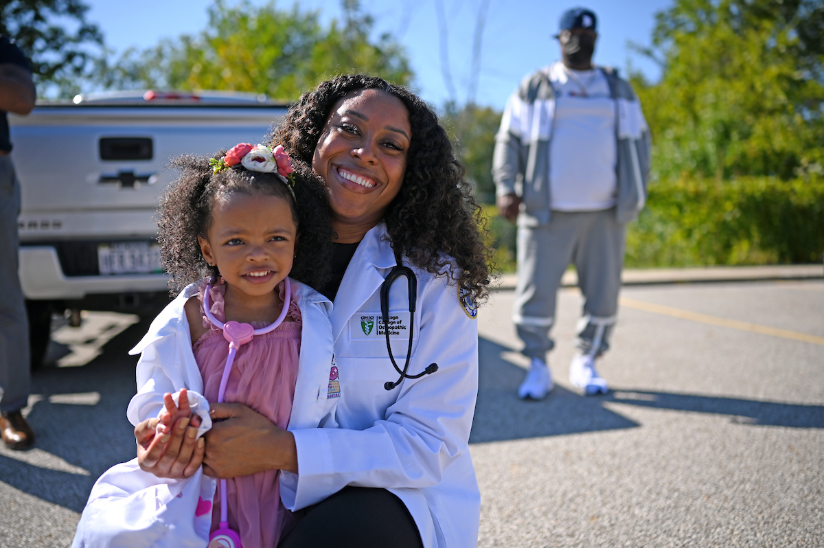 A Heritage College student poses for a photo with a child dressed as a physician