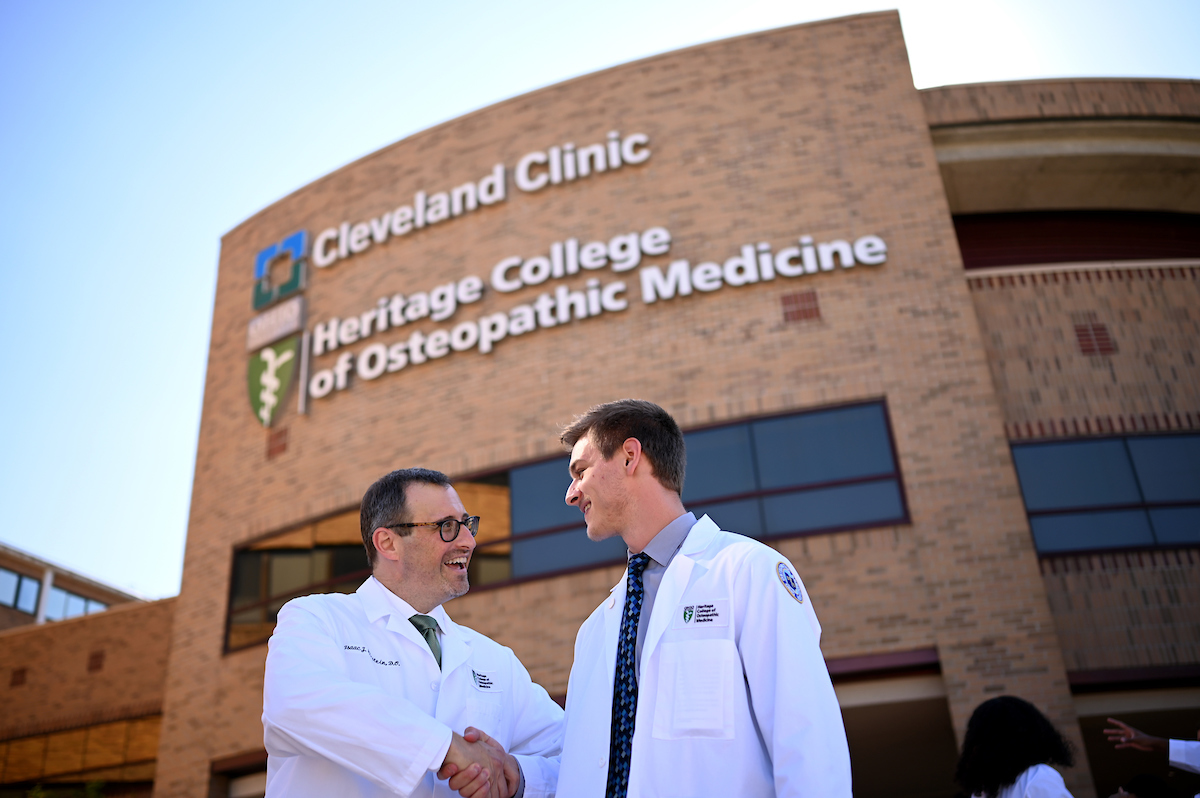 Isaac Kirstein, DO, shaking hands with a Heritage College student outside the Cleveland Campus