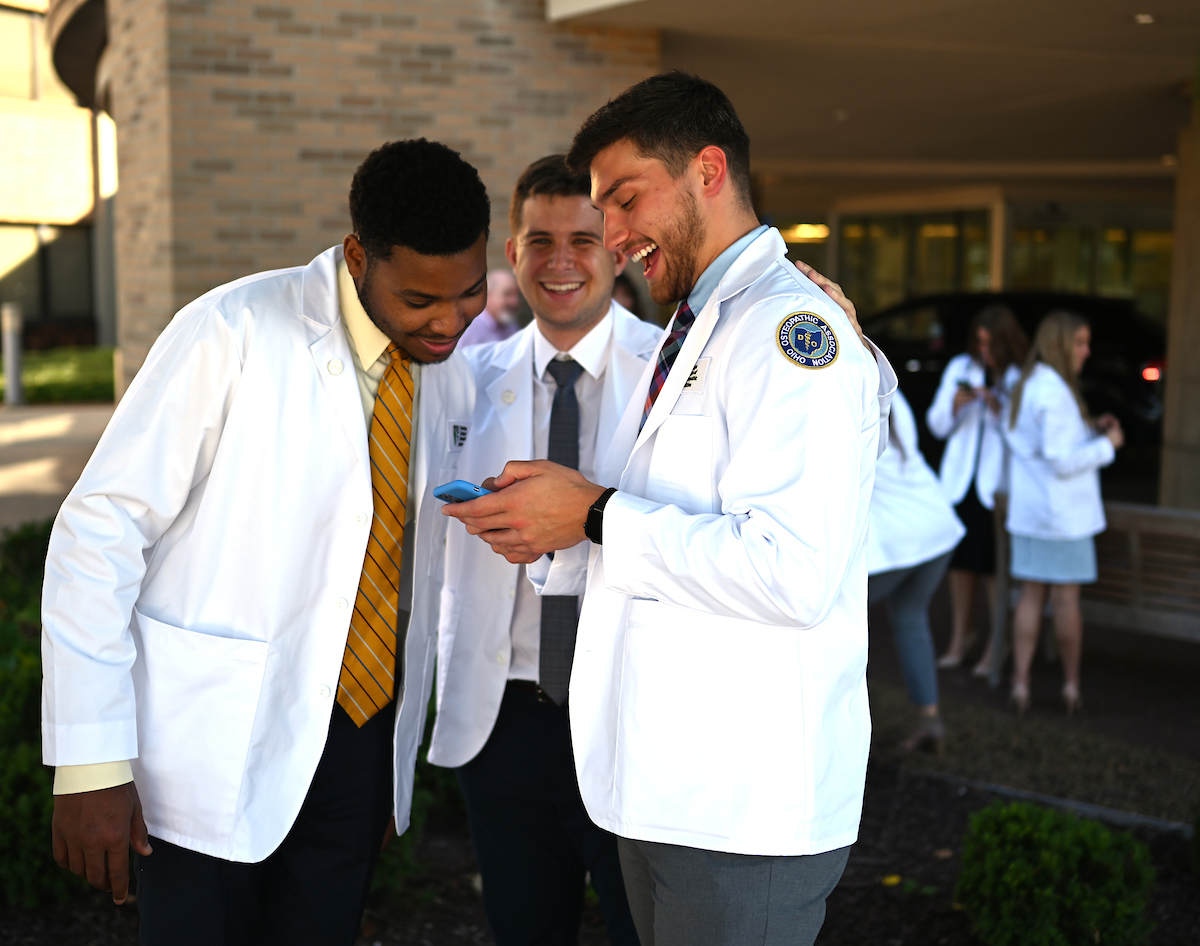 Three Heritage College students looking at a smartphone together