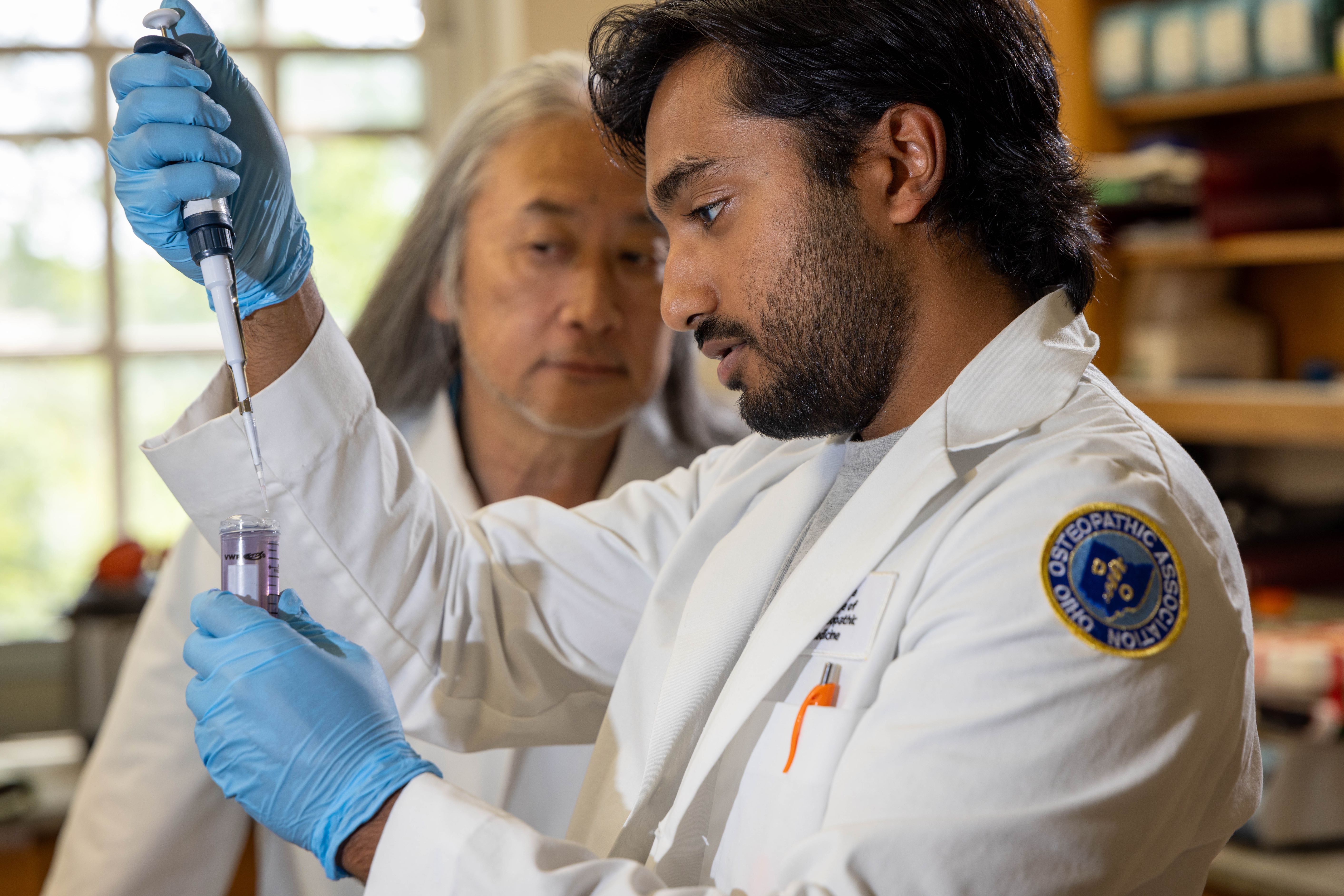 Research mentor, Dr. Nick Okada, overseeing research fellow, Shashank Reddy in lab.