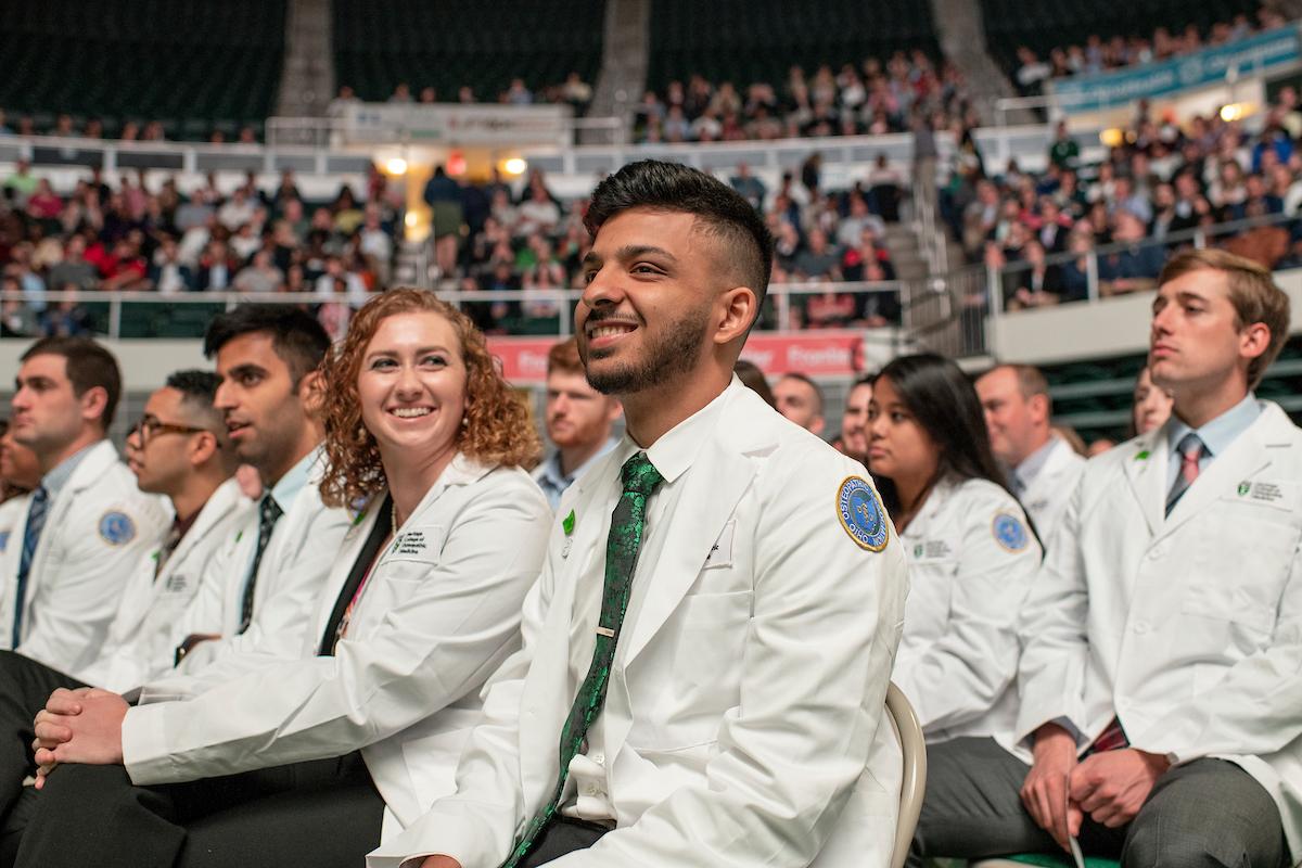 Students smile while wearing medical white coats