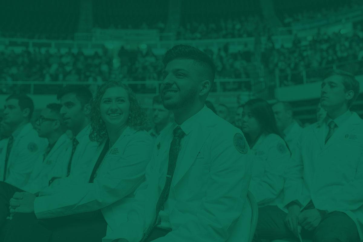 College of Medicine students smile while wearing their white coats