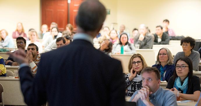 man speaking in front of room full of people