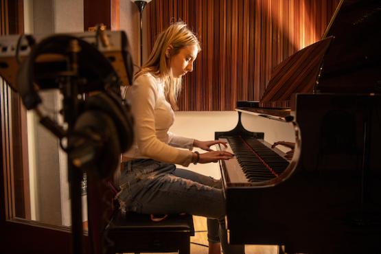 Student plays the piano in a sound recording studio