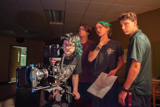 Students stand behind a camera