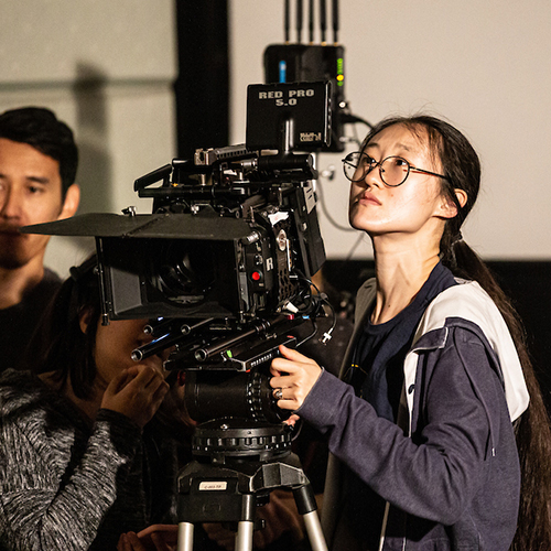 Student works a large camera on set