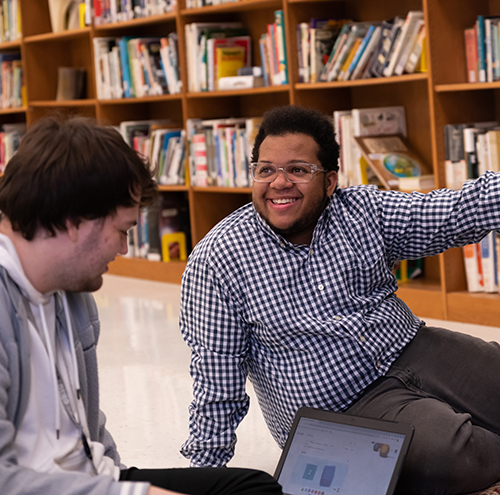 Student smiles in front of bookshelves full of books