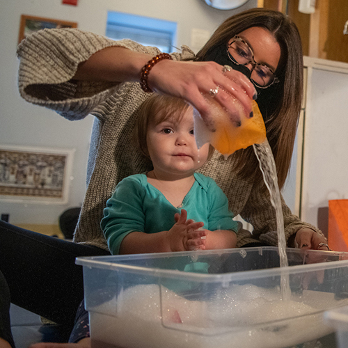 A Patton College student entertains a preschool child with water