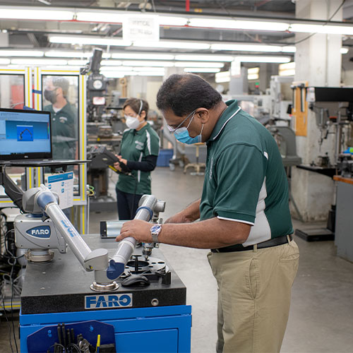 Man working at lab station holding robotic arm